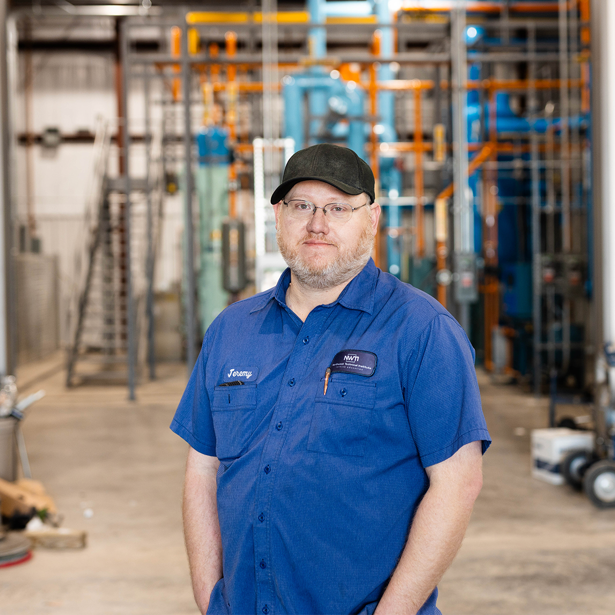 PHOTO:  Jeremy Sherman smiling in front of ammonia refrigeration system