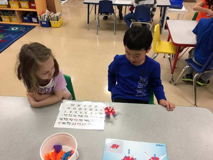 two kids looking an activity sheet, at a classroom