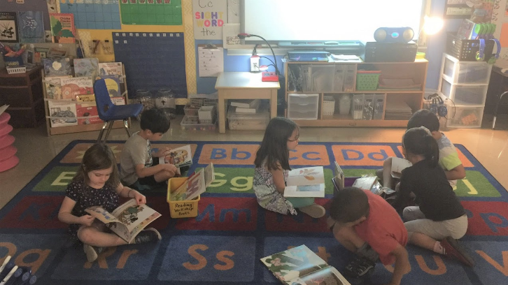 several kids reading on the floor some books, at a classroom