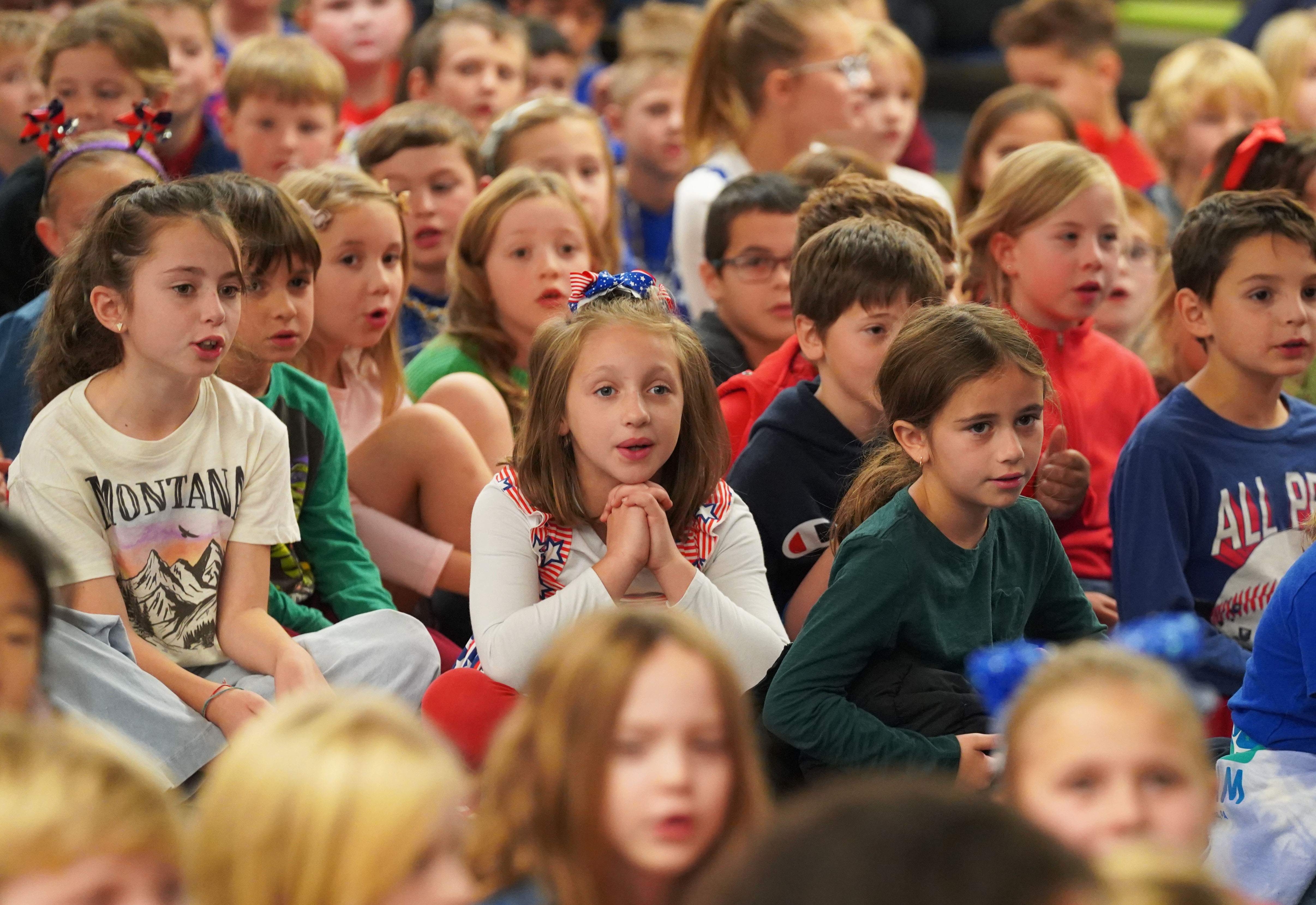 Students sit together during Veterans Day ceremony.