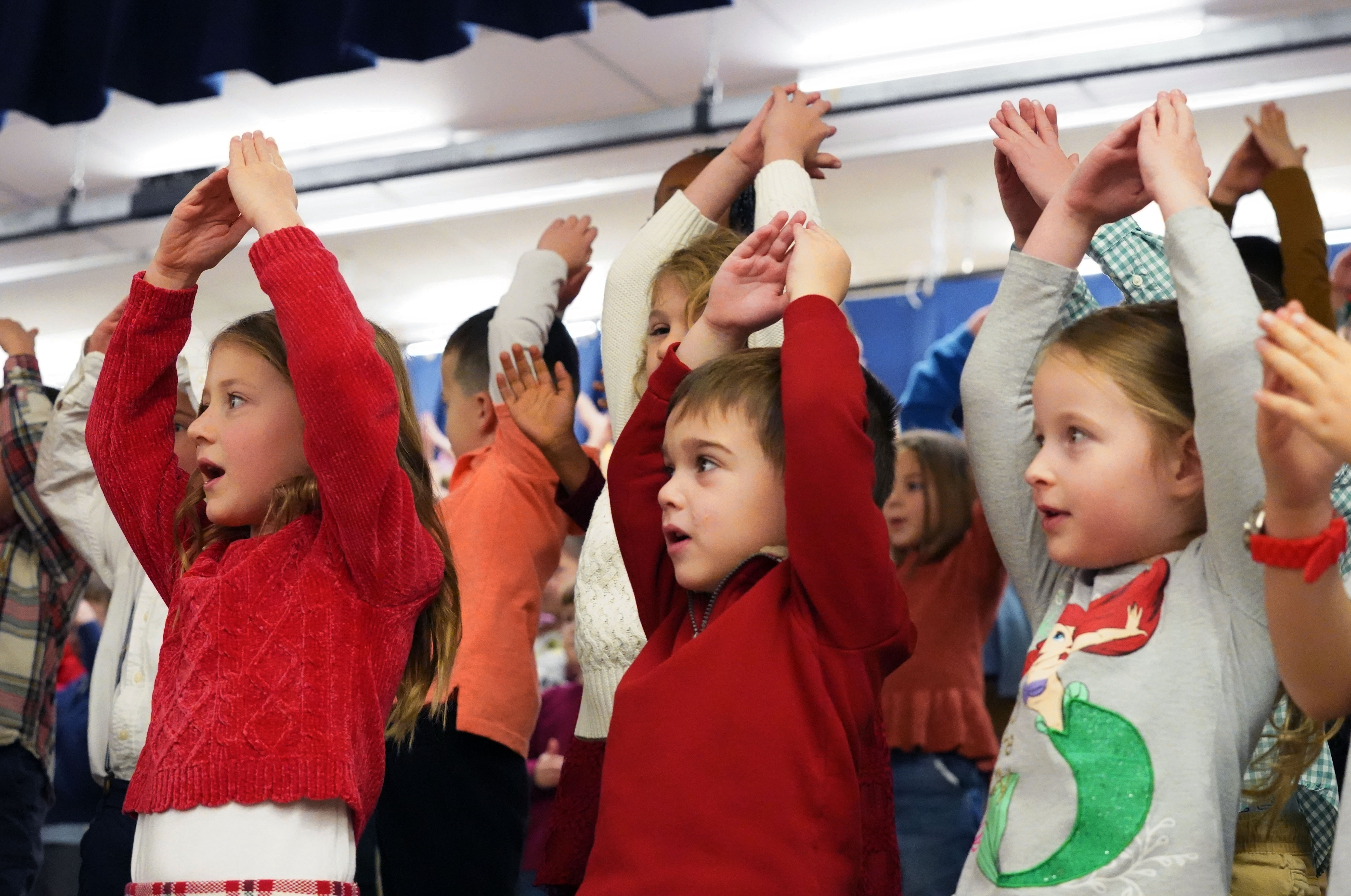 Kindergartners sing and dance in chorus.