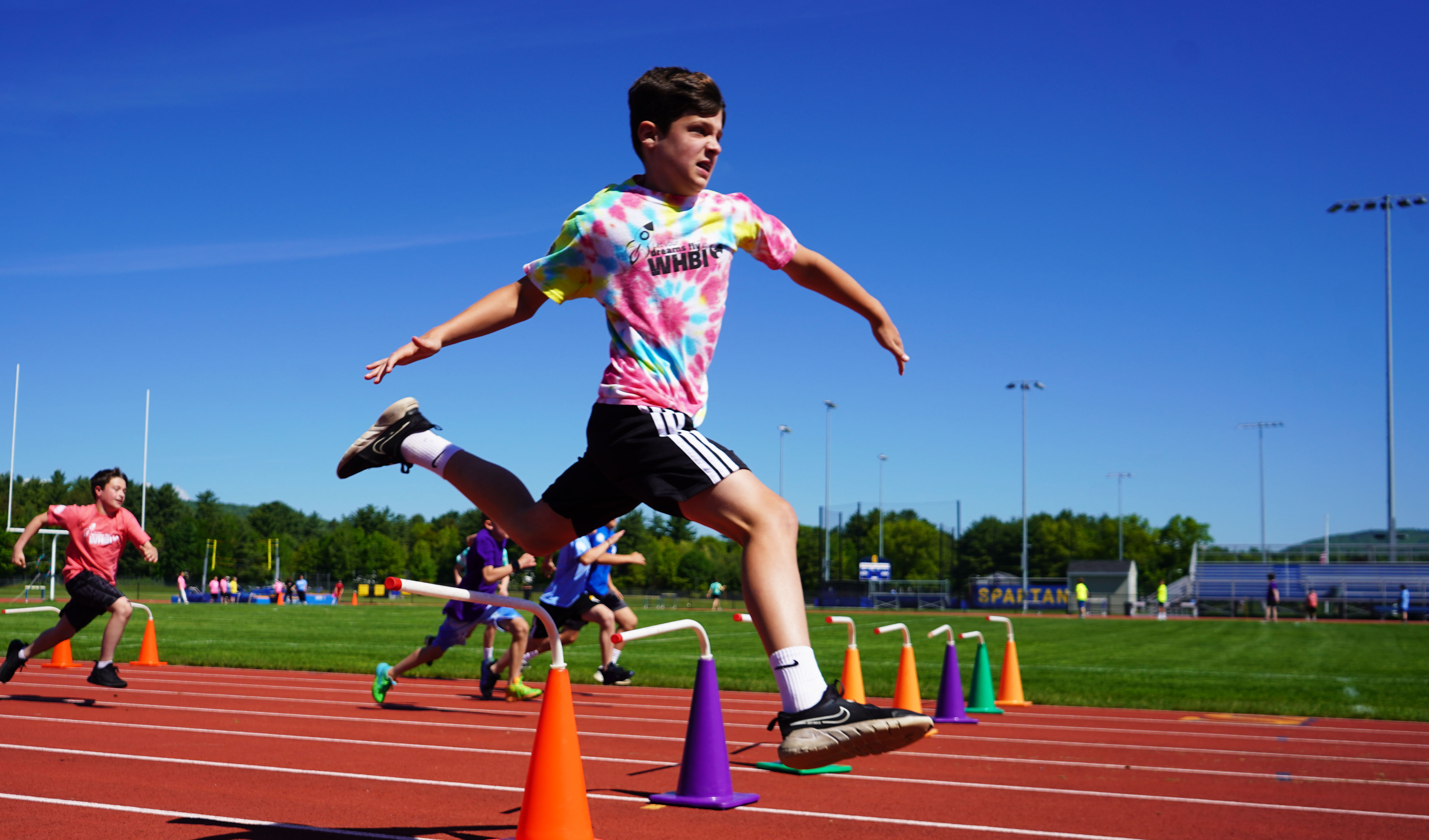 Boy jumps over hurdle during Field Day.