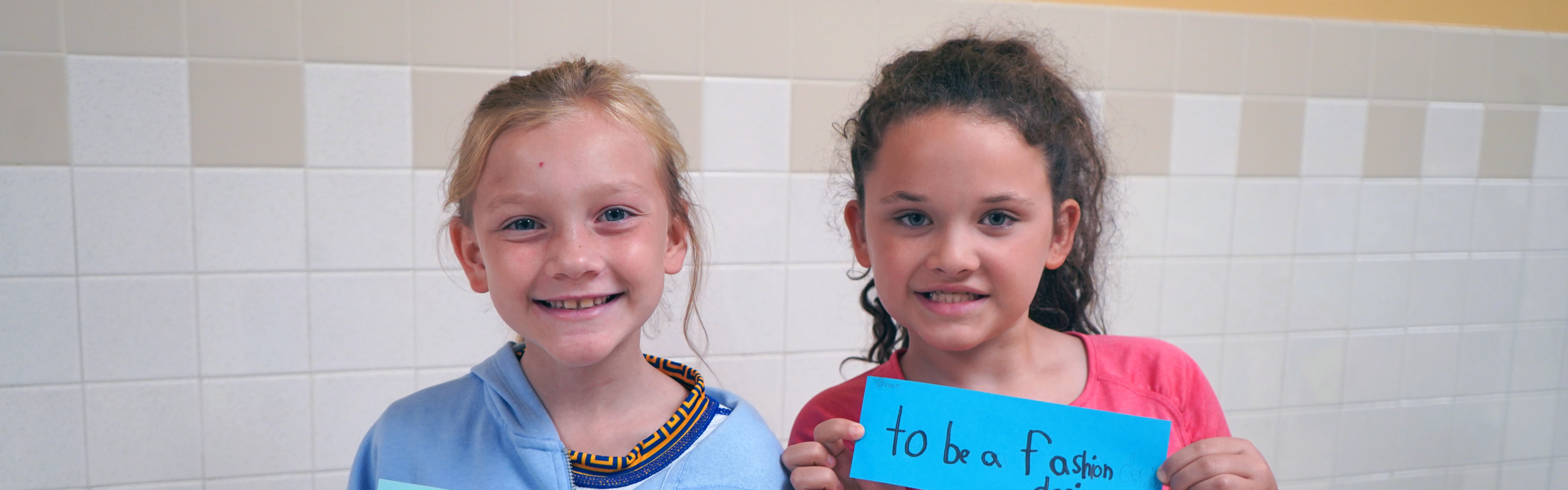 Two students hold up signs with their dreams written on them.