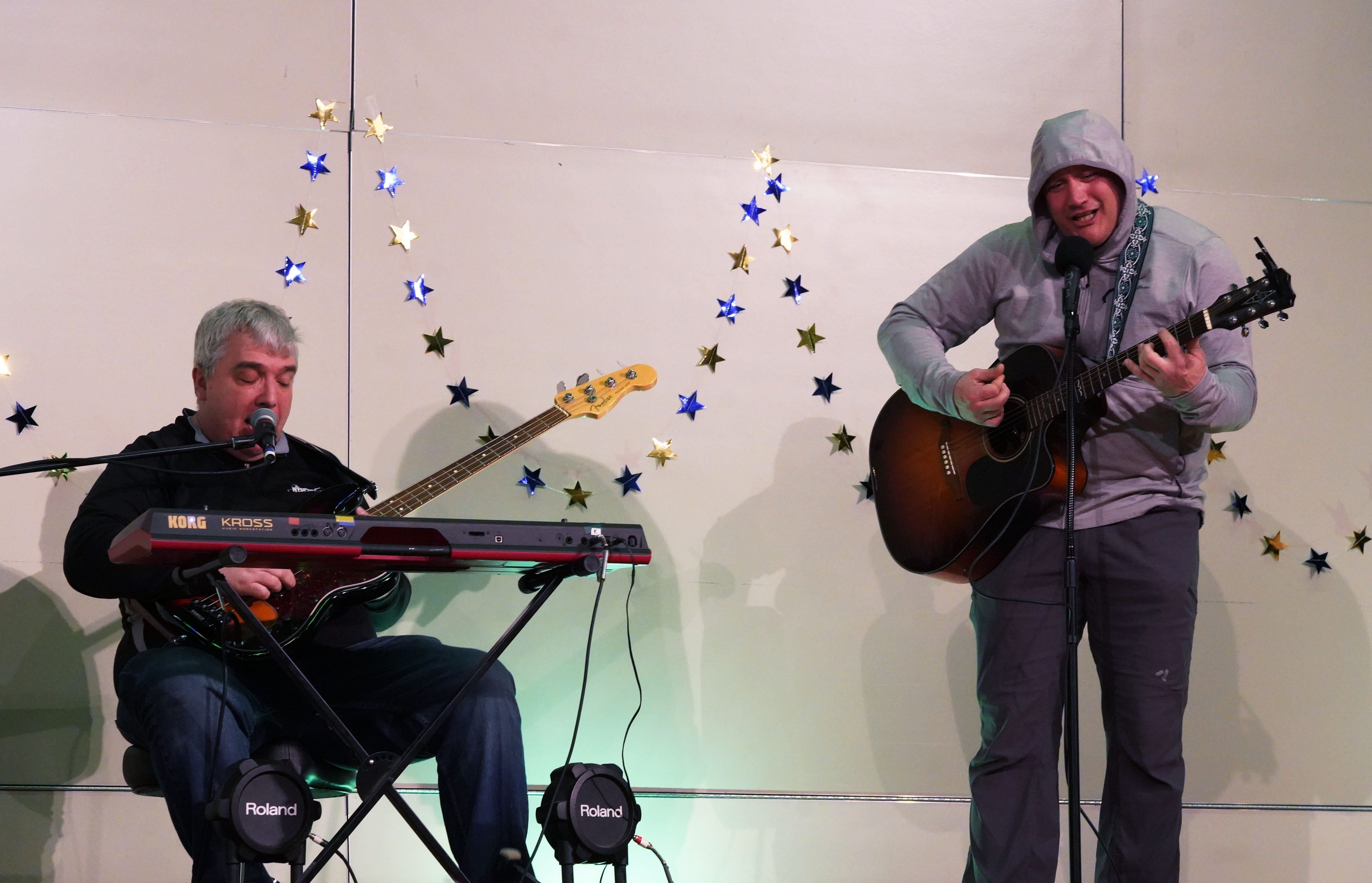 Two teachers sing and play instruments on stage during talent show.