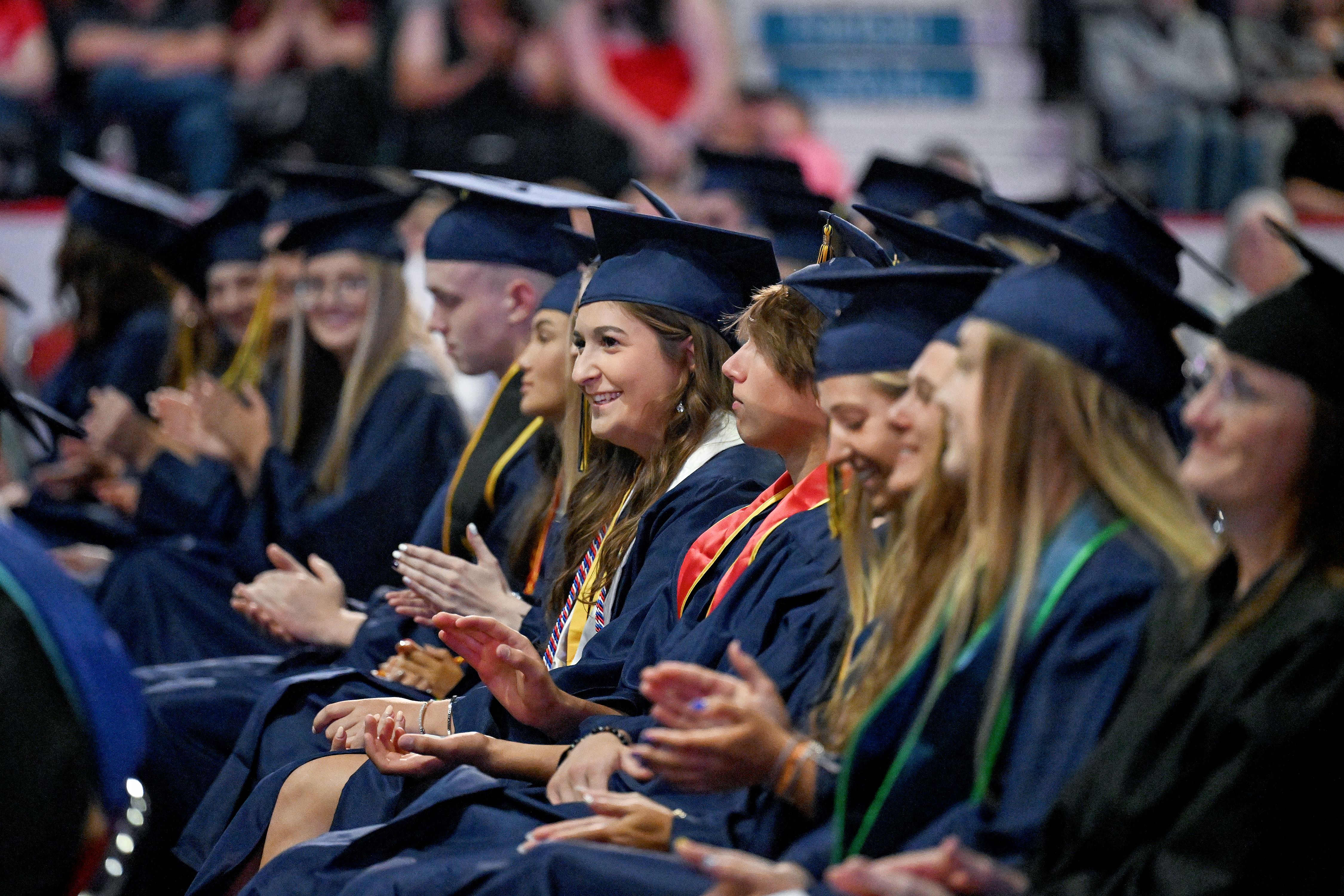 Graduates applaud during graduation ceremony.