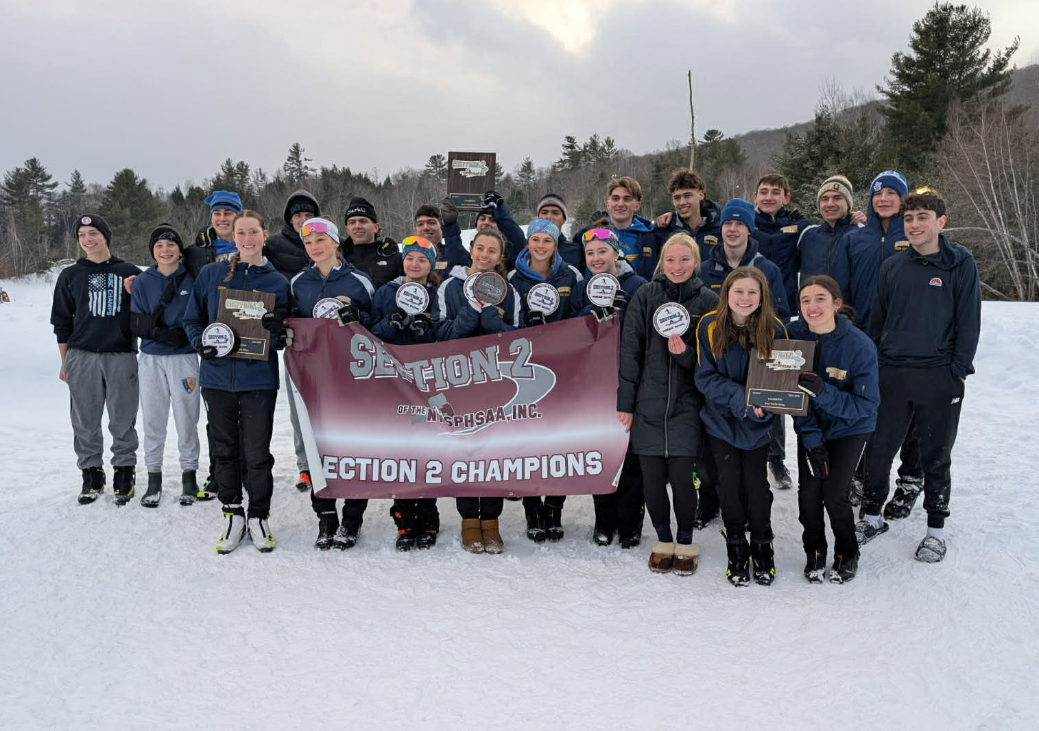 Girls and boys Nordic skiers stand with Section 2 champions banner.