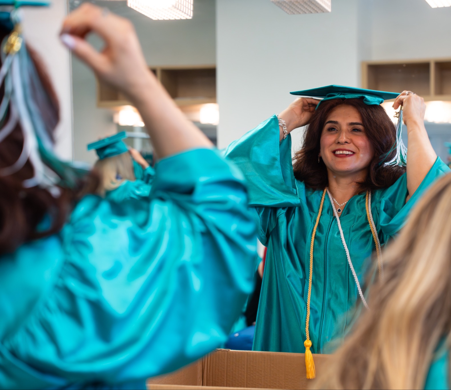 Excel Center Graduate putting on their cap and gown