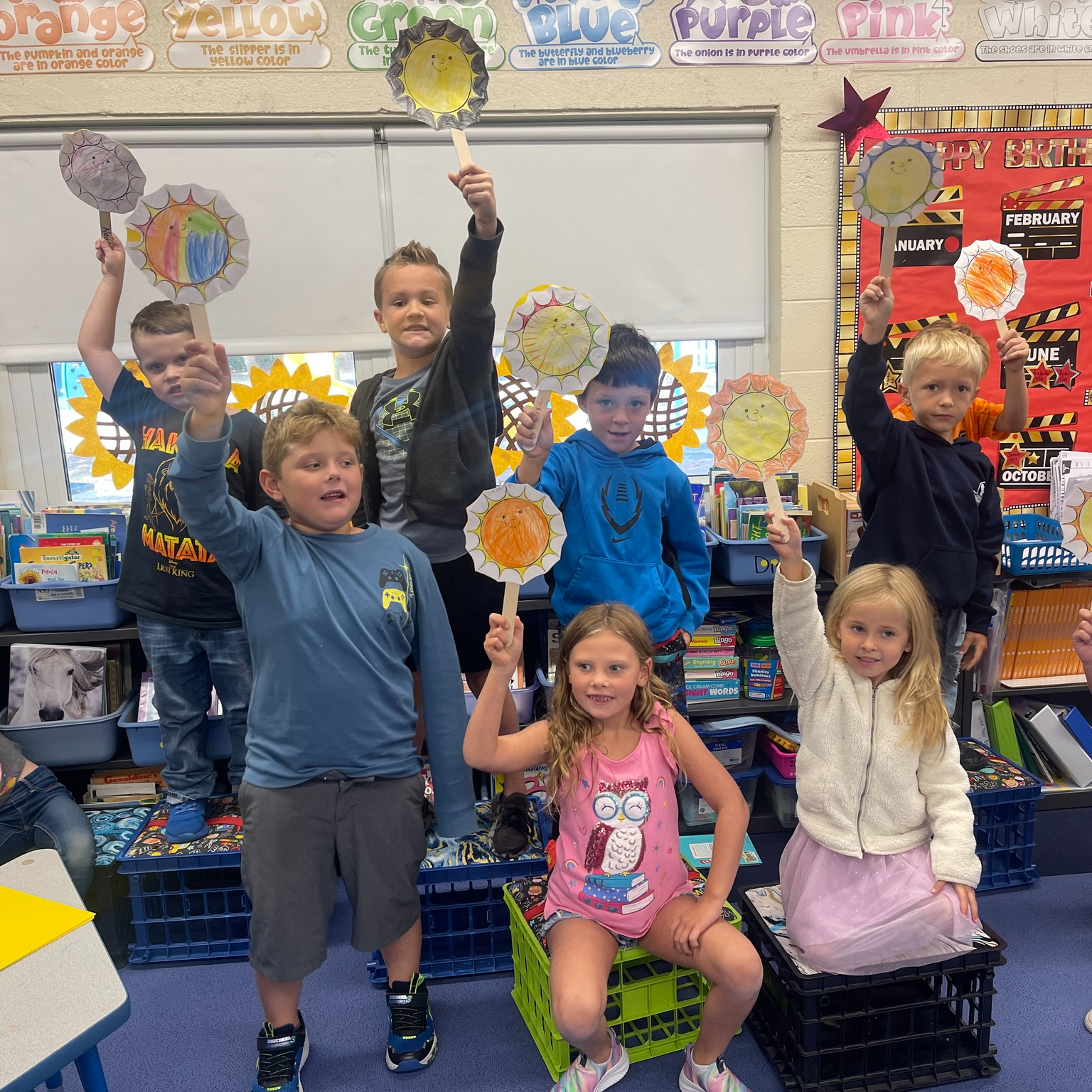 students holding up crafts of the sun in a classroom