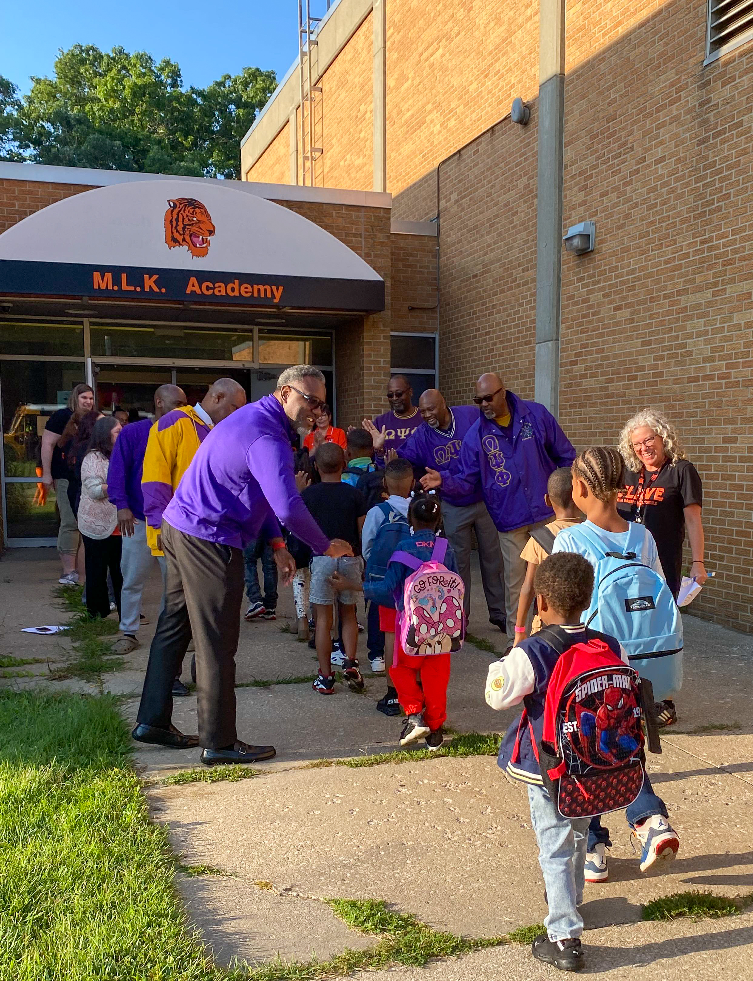 Students walking into building and receiving high fives from teachers 