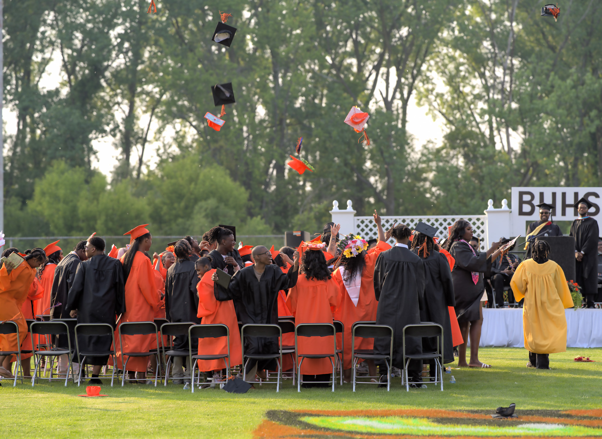 Graduates celebrating outdoors by tossing caps in the air during a graduation ceremony at Benton Harbor High School.