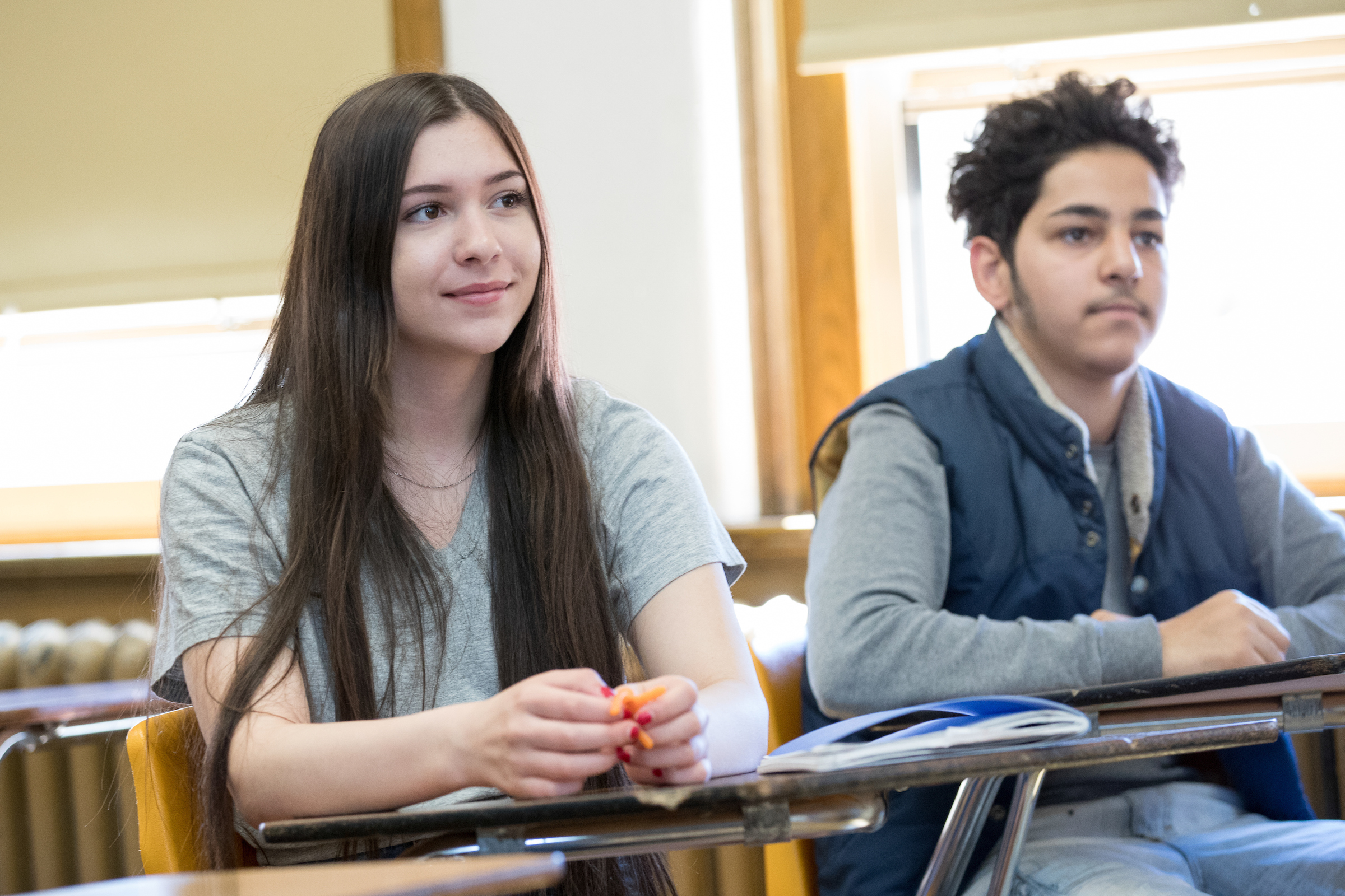 Two teens sitting at classroom desks