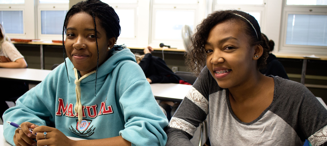 Two teen girls smiling at classroom