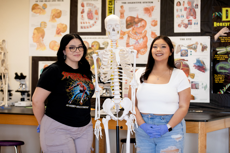 two girls smiling next to a medical prop skeleton