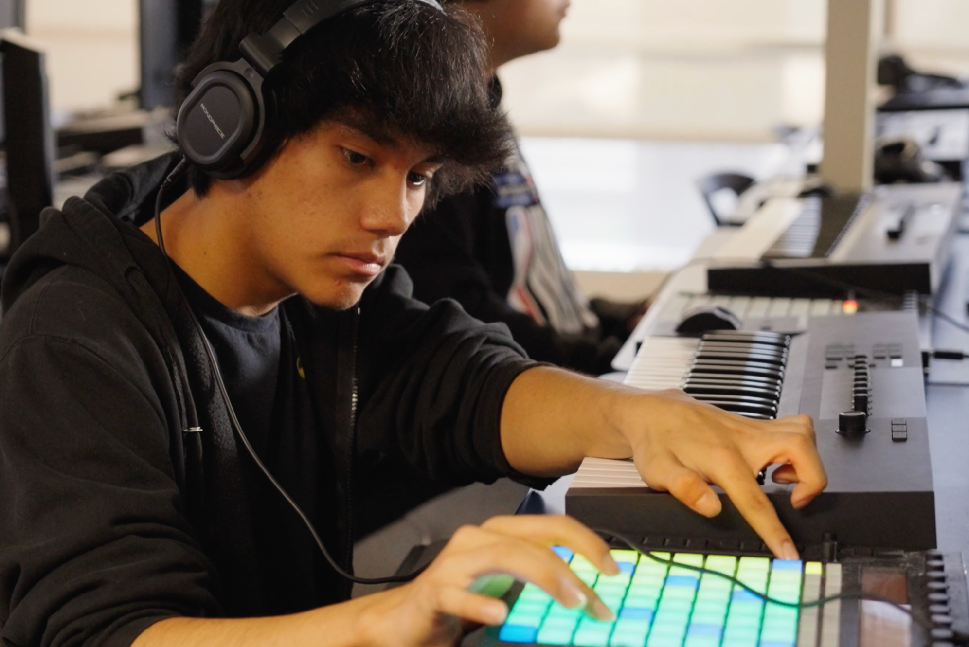 male student working on an audio mixing soundboard while wearing headphones