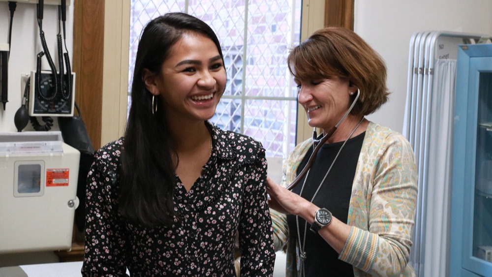 Doctor using stethoscope on young woman 