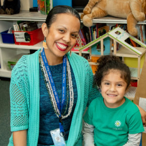 Teacher and girl student smiling at classroom