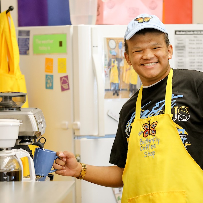 Student in an apron serving coffee