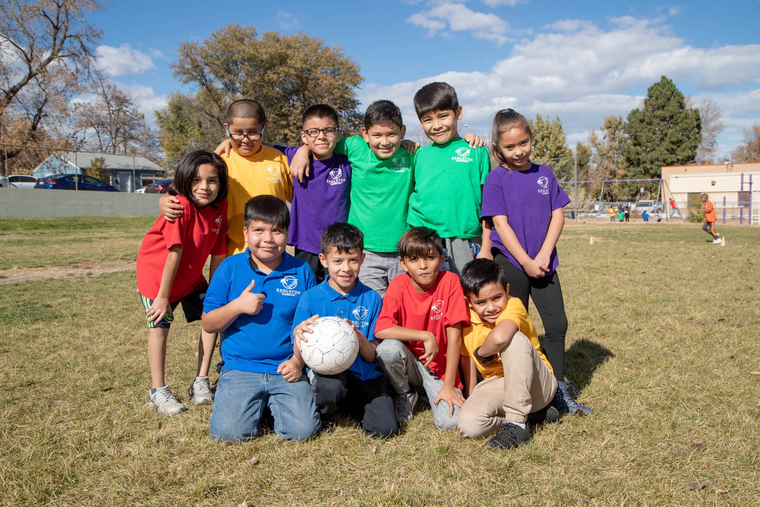 Group of kids posing for photo holding a soccer ball