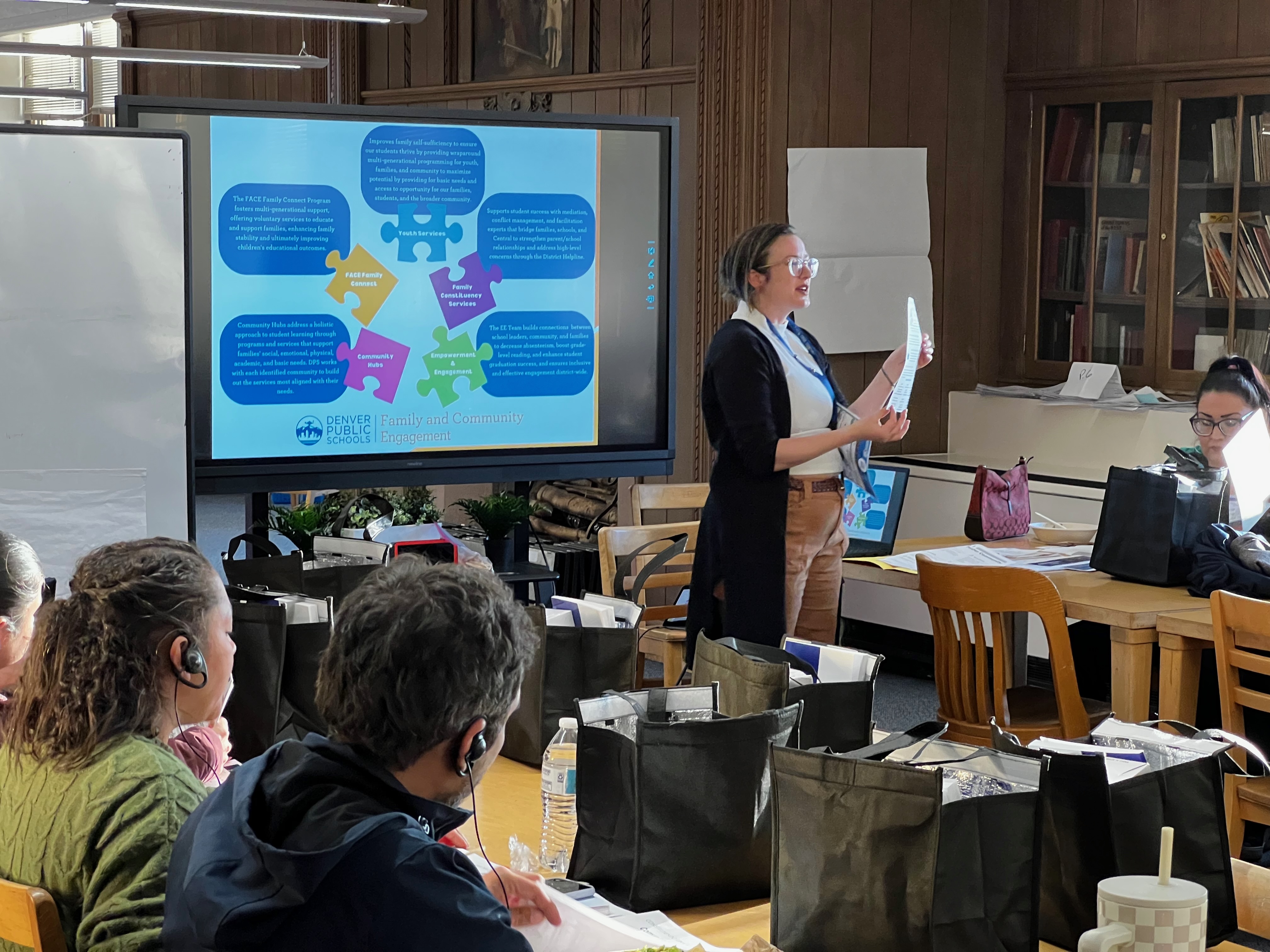 A presenter standing in front of a group of attendees, facilitating a presentation.