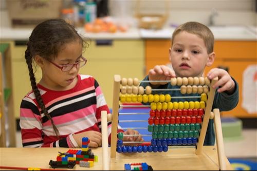 two kids playing with an abacus