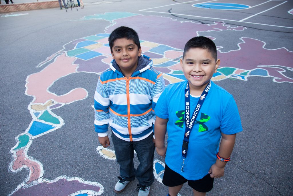 Two elementary children in front of a chalk world map on the pavement