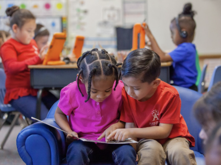two kids reading a book together