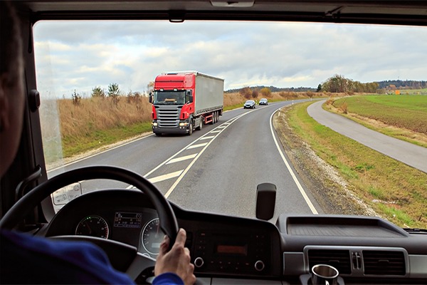 Inside of truck driving cab view. Person driving on road