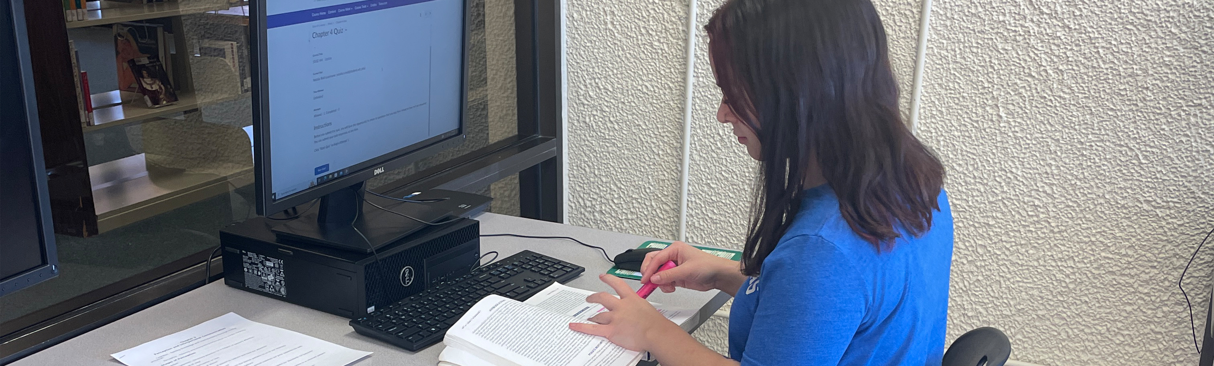 Student working on homework with book and computer