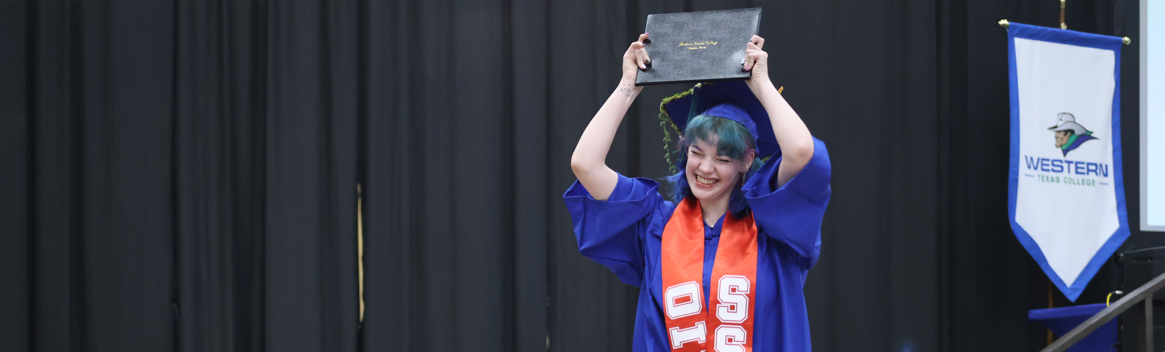 Student holding degree up at graduation