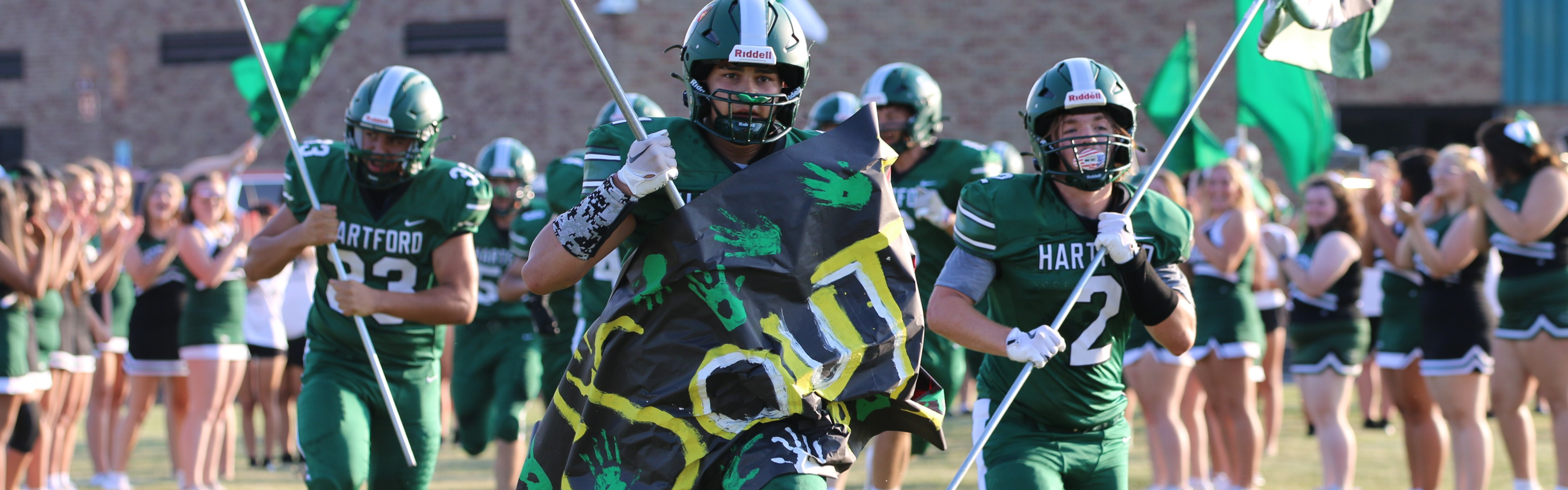 football players run out of the tunnel carry the american flag and hartford flag