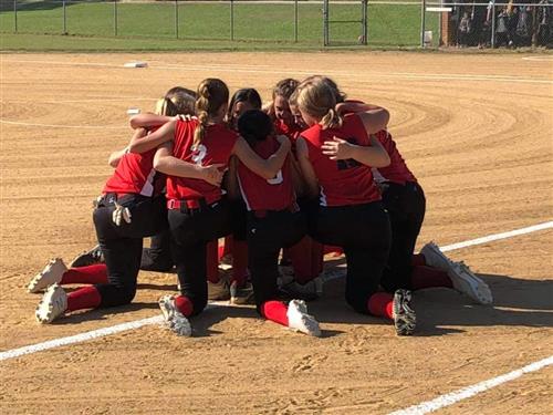 softball team players gathered together discussing probably game plans