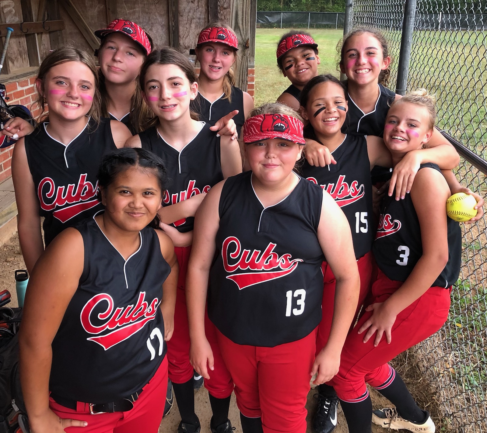 softball team players together after a game, smiling to the camera