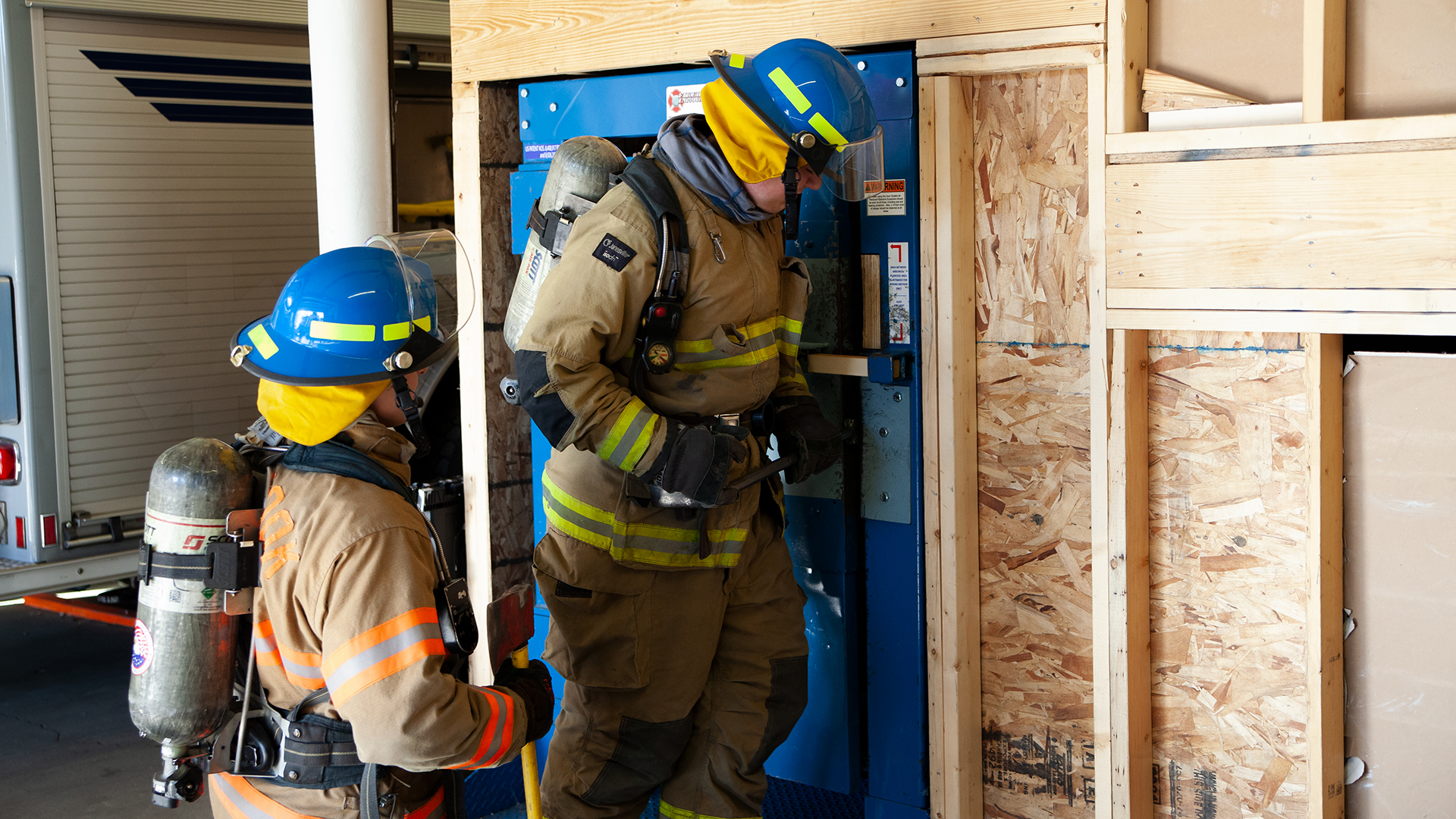 firefighter students practicing breaking through a door