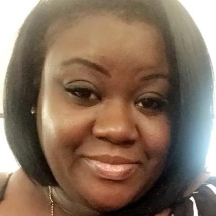 A smiling adult woman with short hair and a white and black striped top poses for a photo.