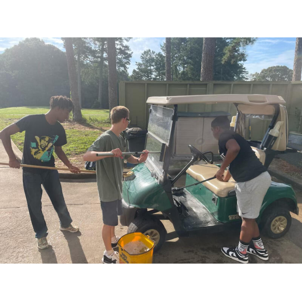 Students cleaning a golf cart