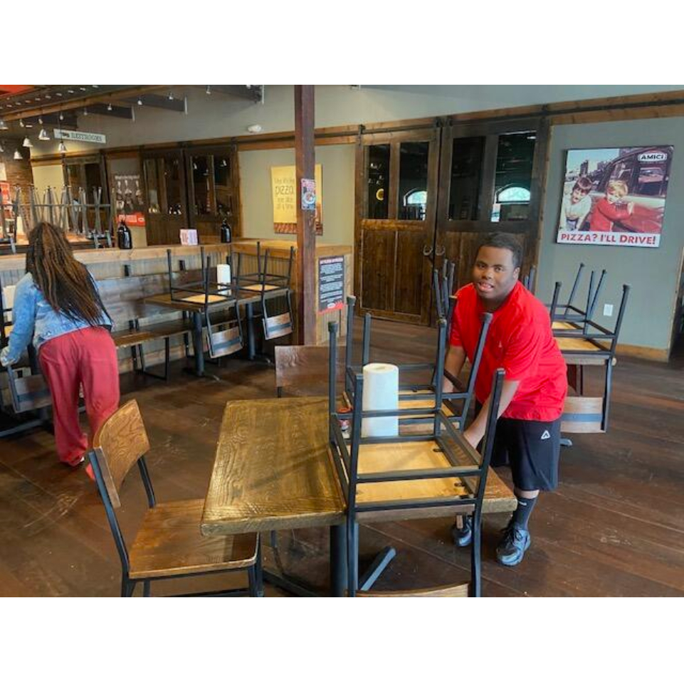 A student putting chairs on a table in a restaurant