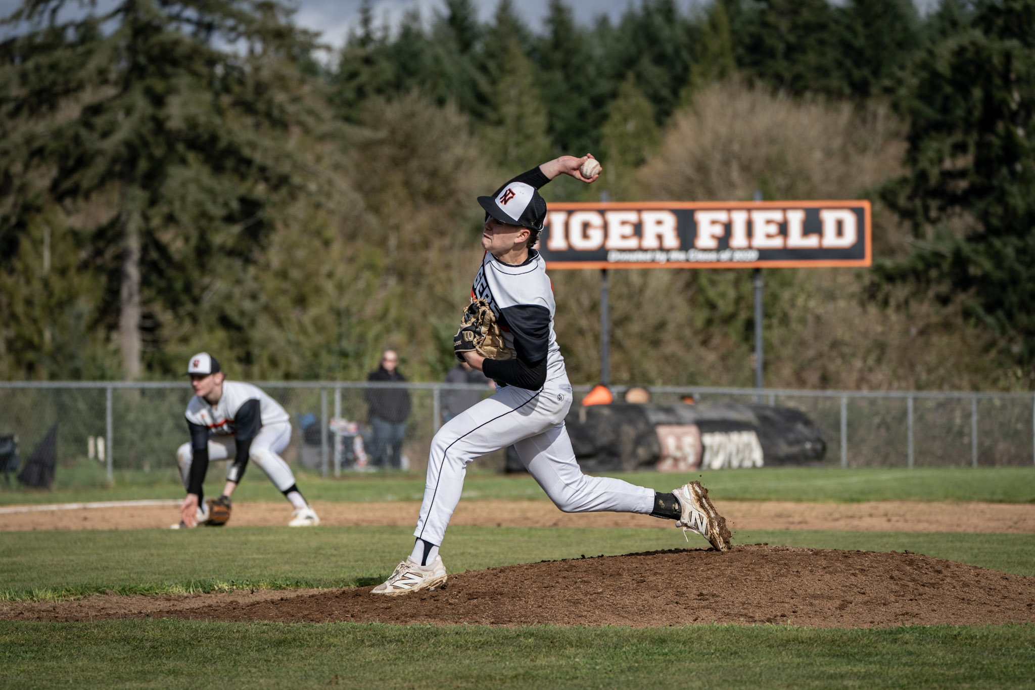 A high school baseball player throws a pitch during a home game