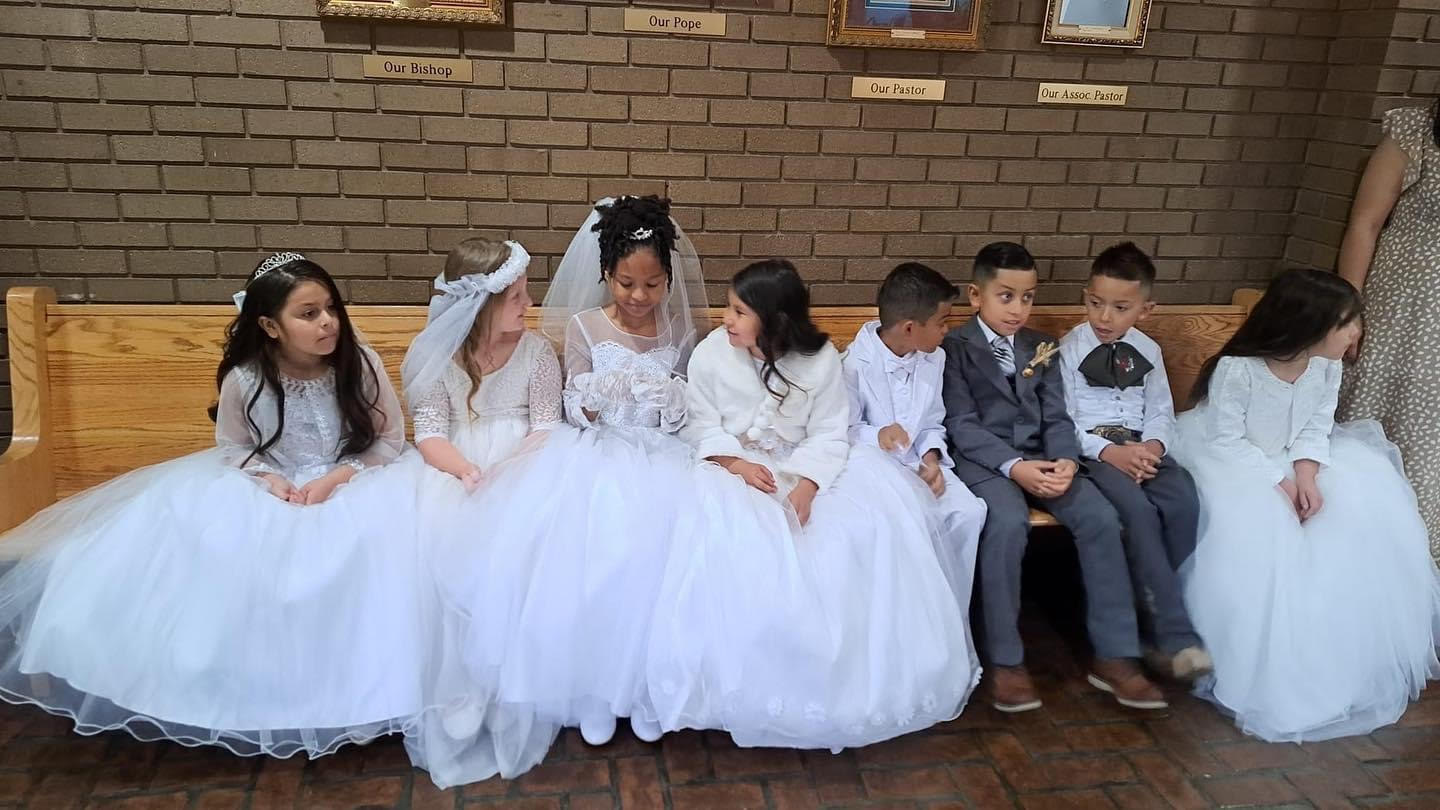 students seated in church in their First Communion outfits