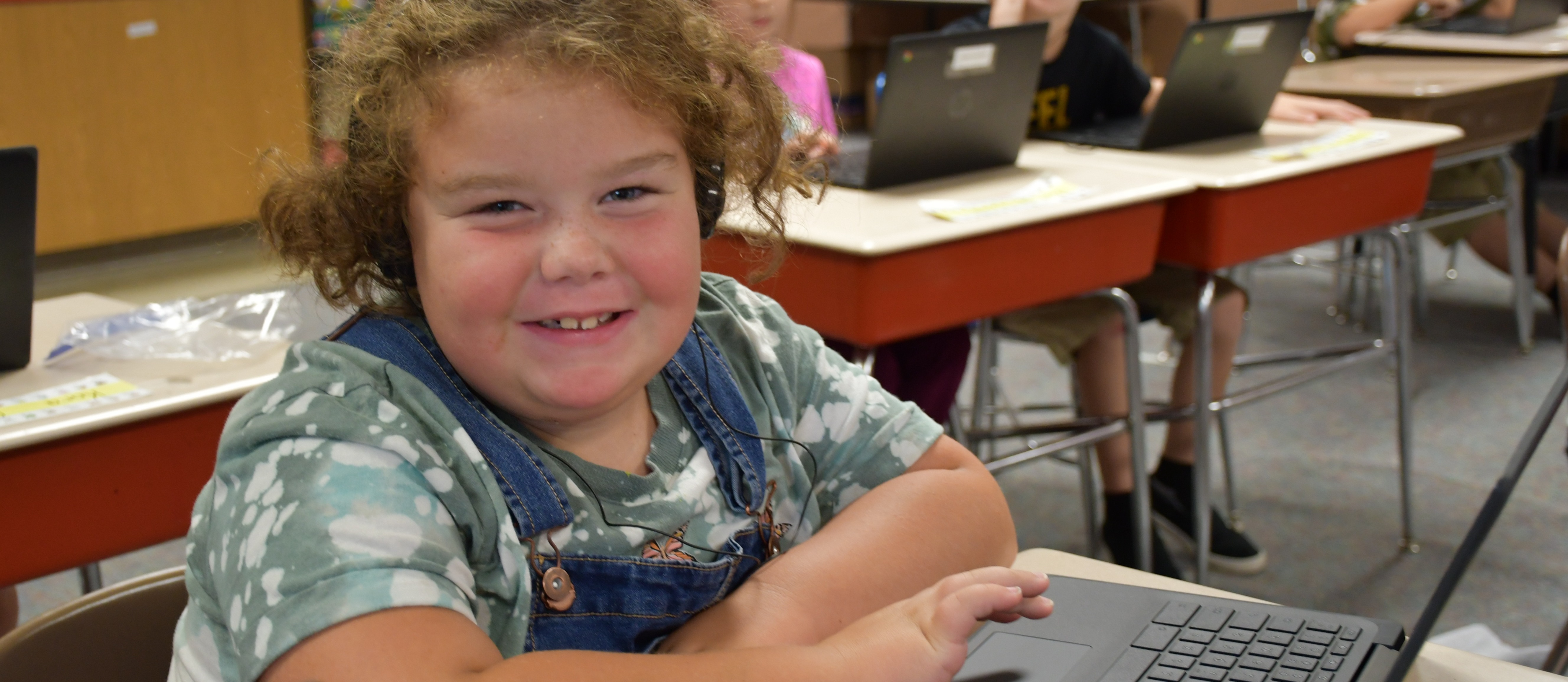 young girl looks up from her computer and smiles