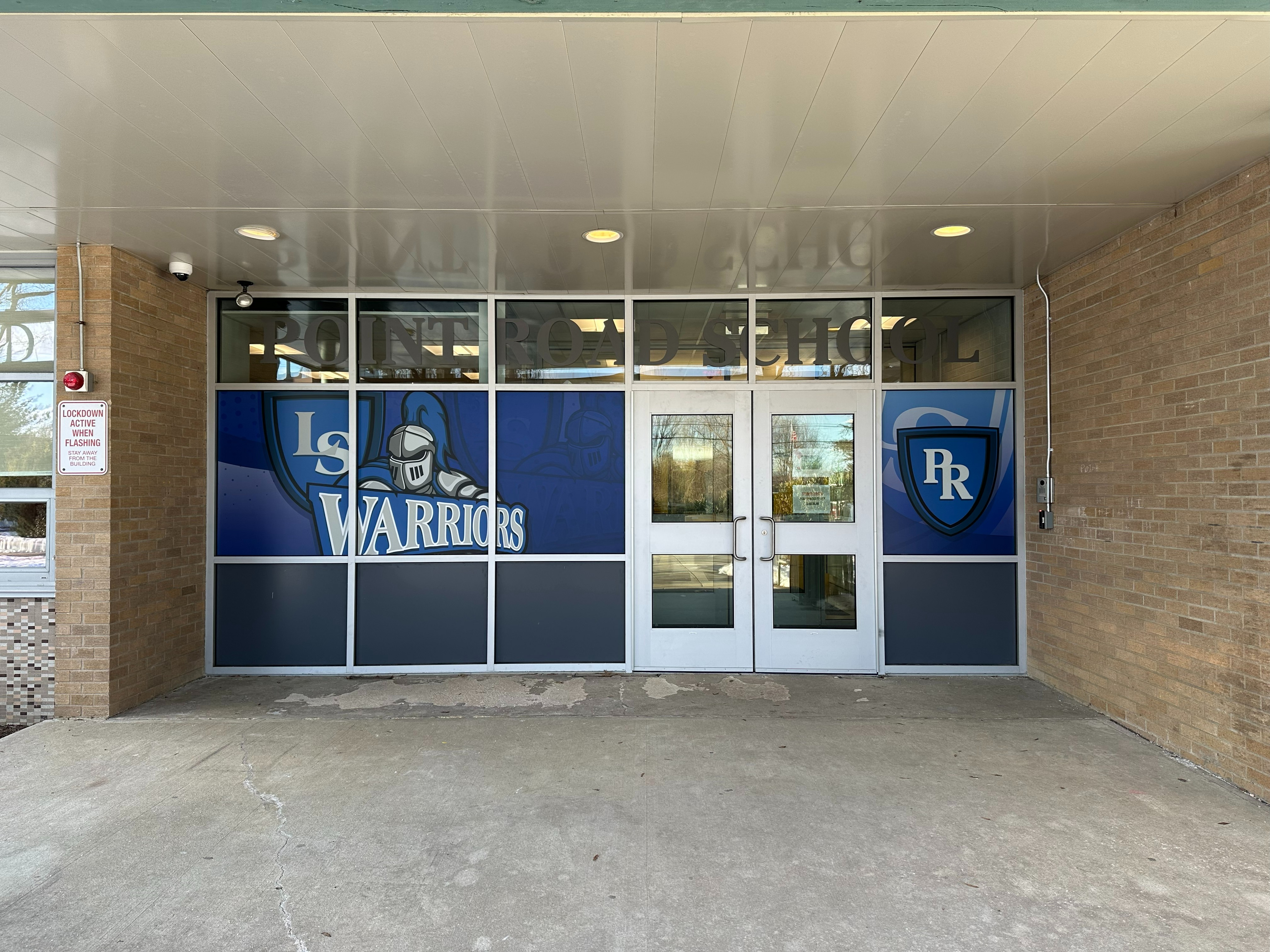 Point Road entrance with several glass panels with the LS warrior knight, double doors, and access control on wall to right