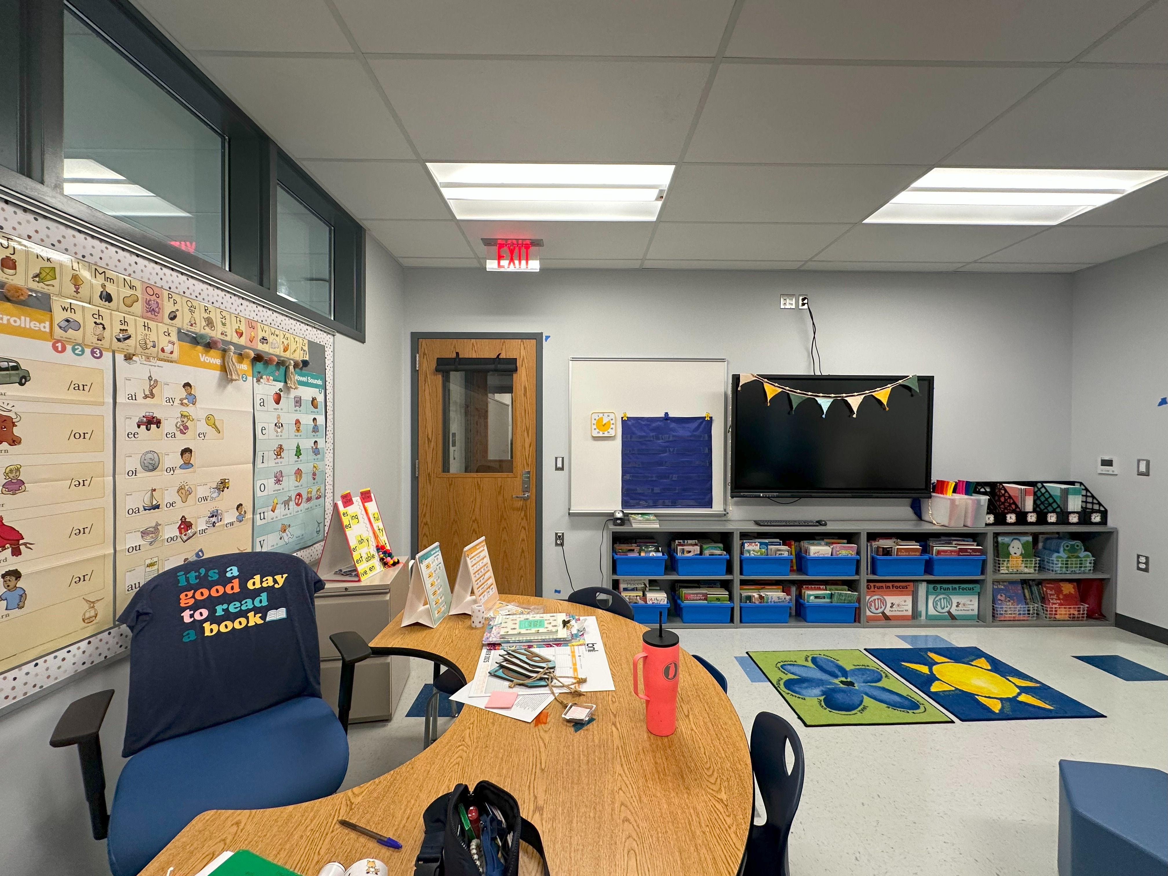 small classroom with windows up to the left, table, tv, and open shelving