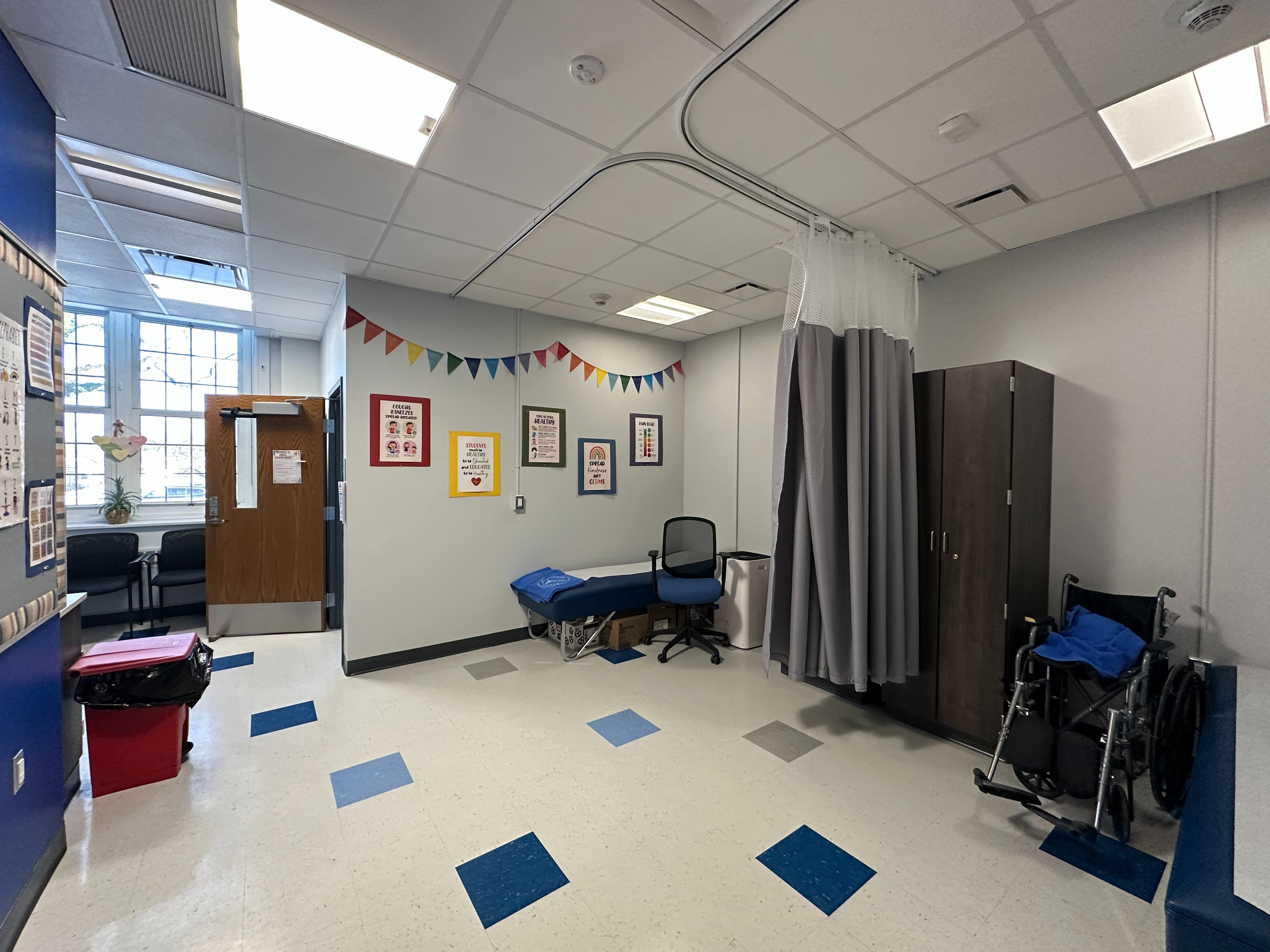 Nurse's Office with wheelchair, curtain, cabinets, and seating