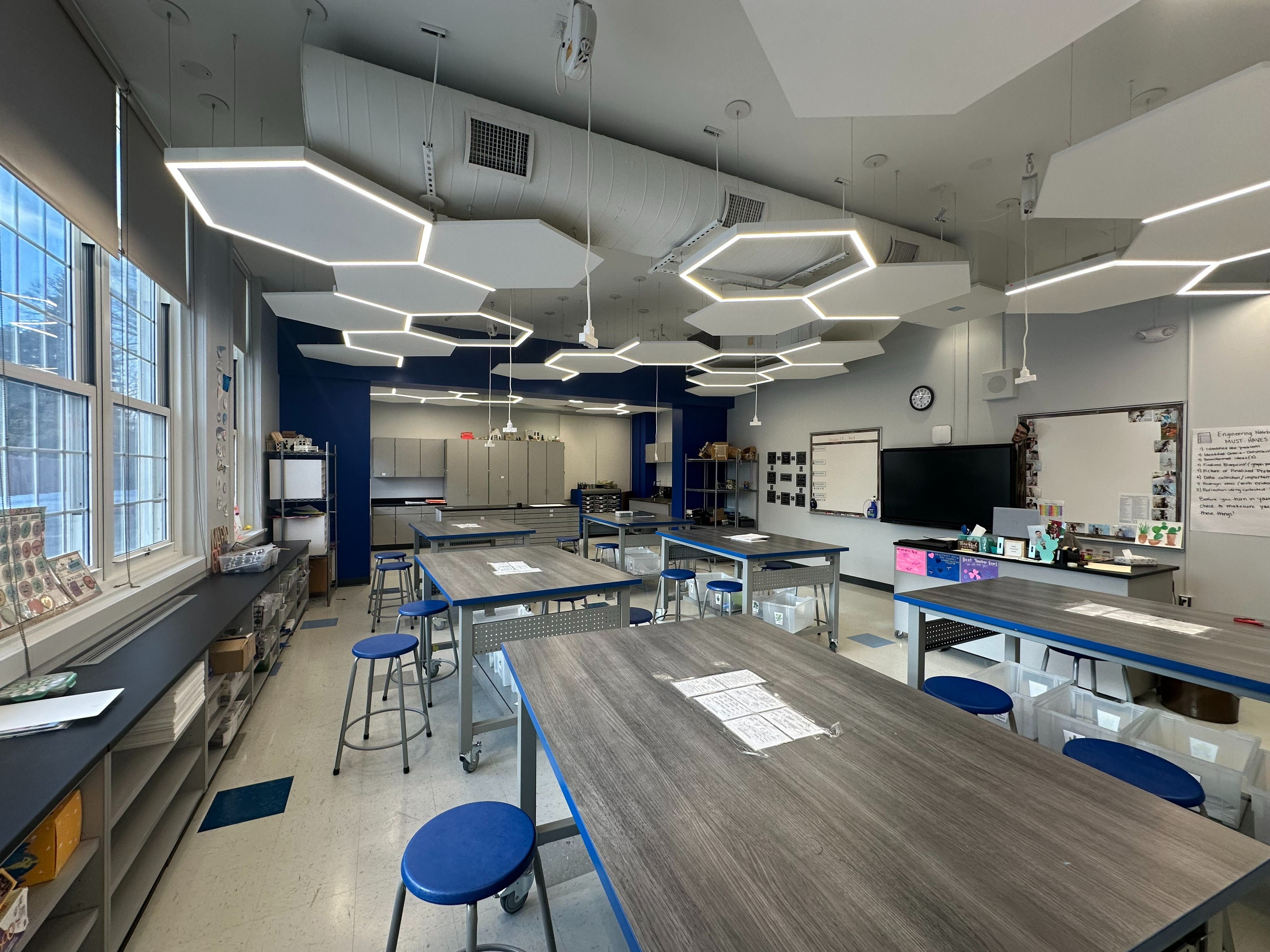 stem room with lighting and electric reels hanging from ceiling, tables with wheels, stools.