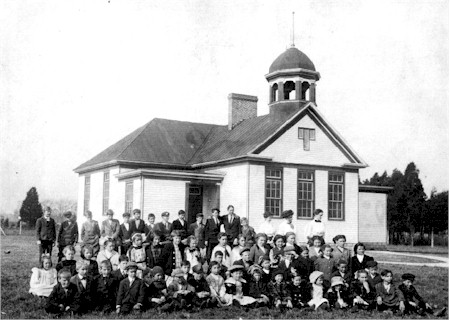 Black and white vintage photo of a two story school building and approximately 40 students out front