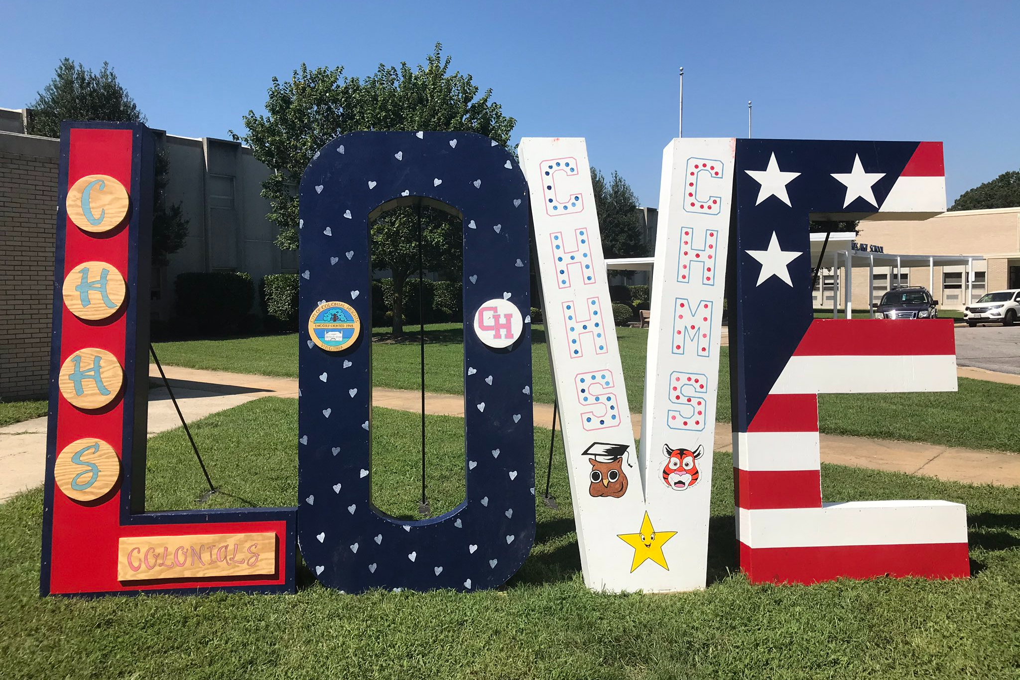 Large wooden letters spelling out LOVE are on display outside of CHHS. The letters feature Colonial Heights colors and logos.