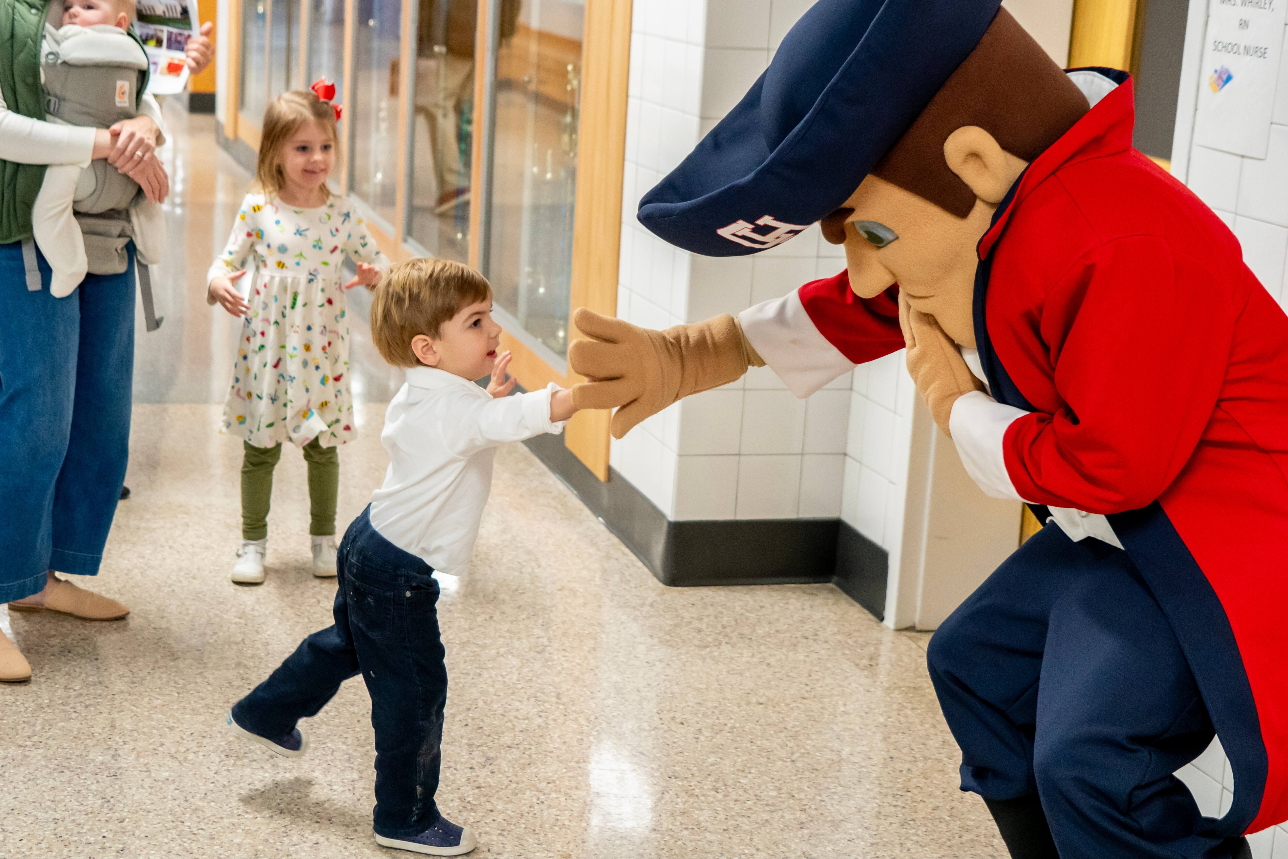 Colonial mascot man high fives small child -- a teacher's child