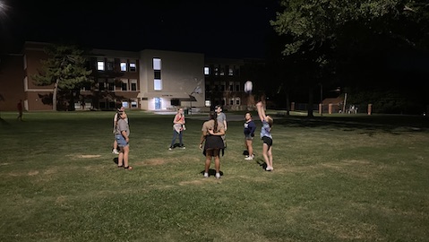 Team members playing with a volleyball in the dark