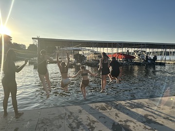 team members jumping from the dock into the lake