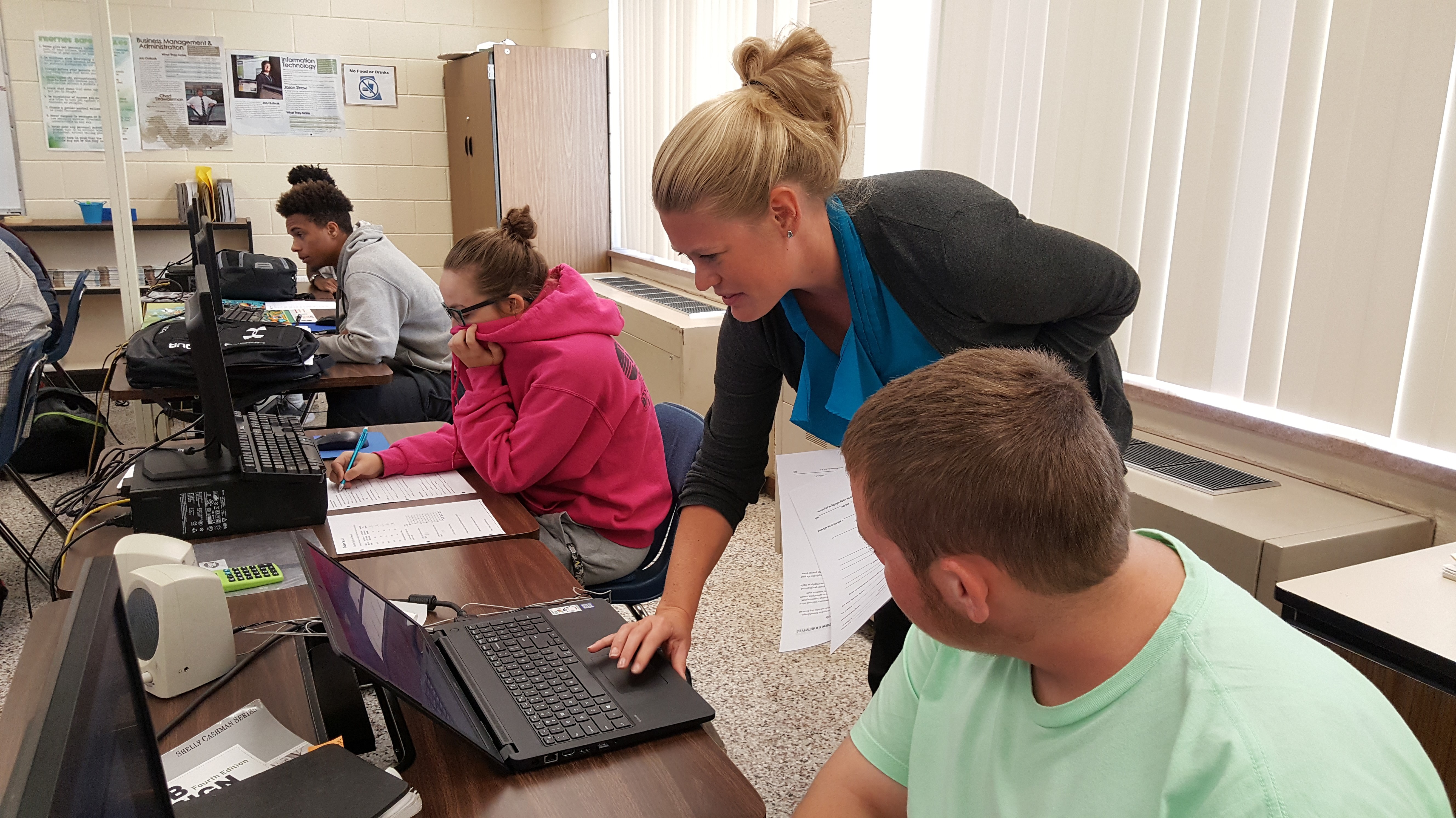students in class with teacher helping them