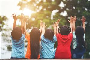 Children outside raising their hands